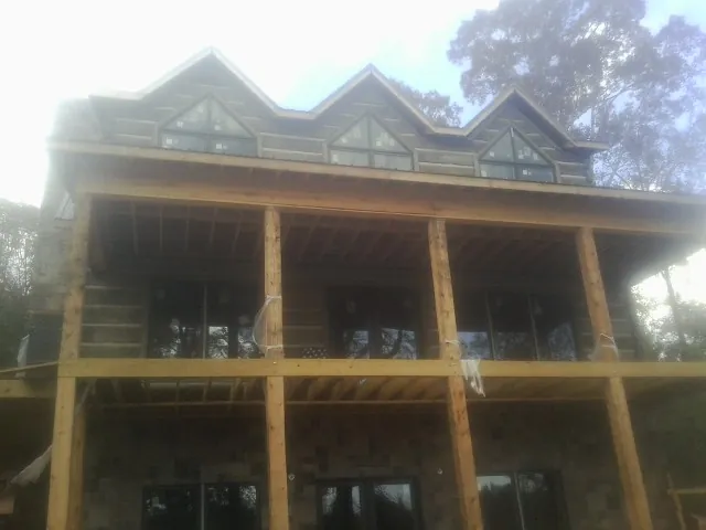 Dormers and porch framing on a large log home under construction — Roof Coating work by our crew in Savona