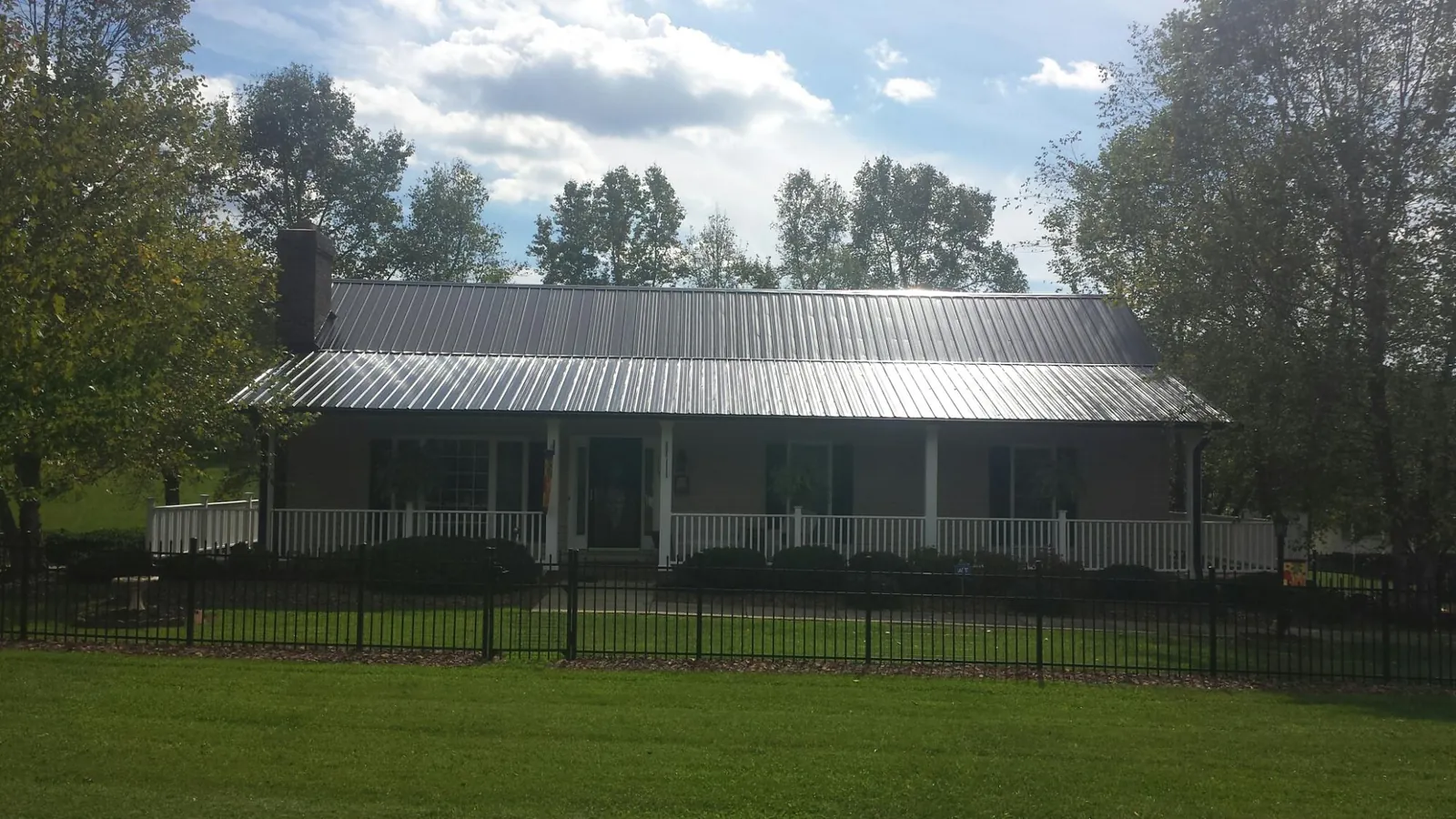 Gray metal roof on a brick ranch with a full width front porch — Gutter Guard Installation work by our crew in Savona