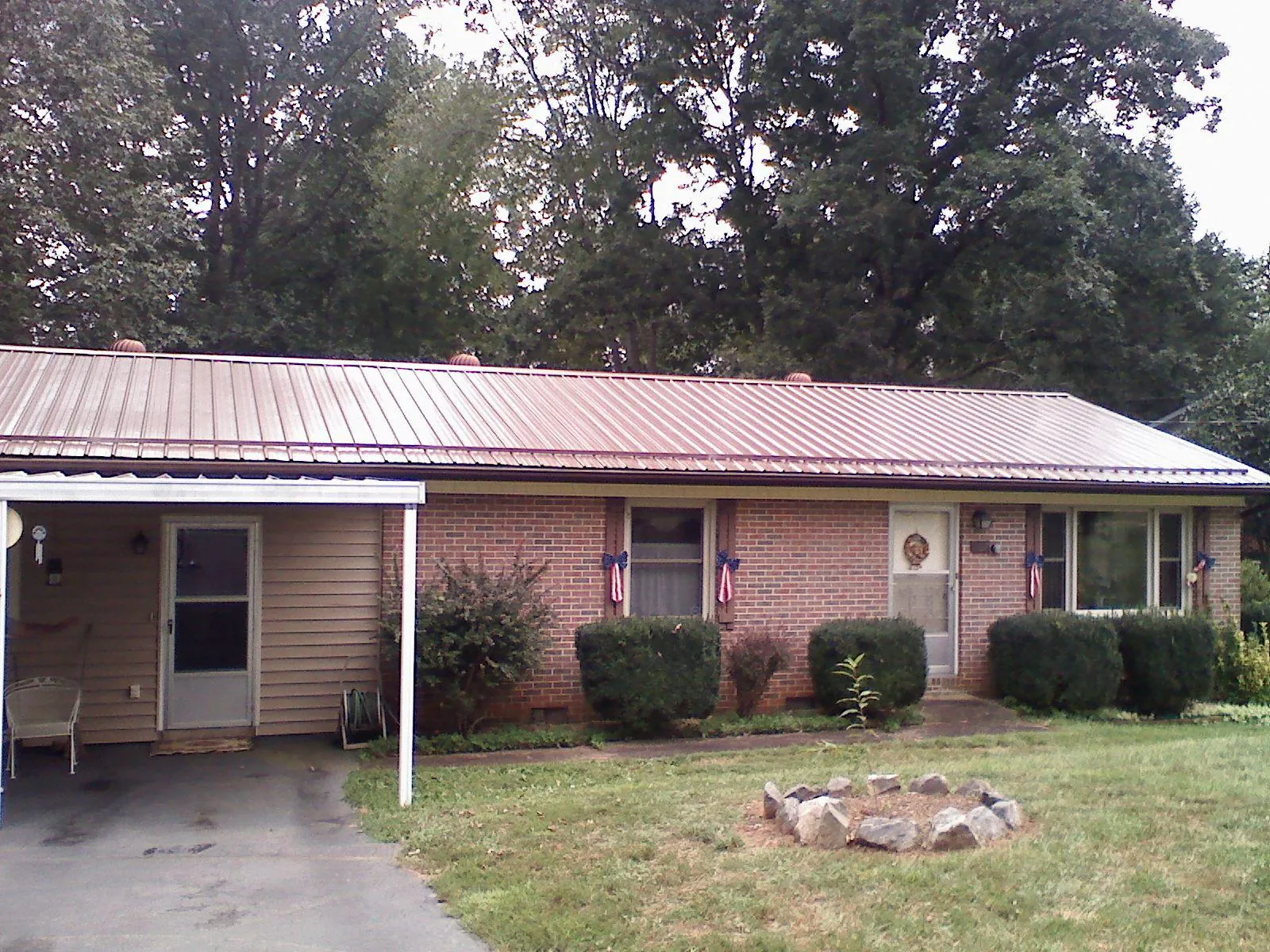 Bronze metal roof and carport on a brick ranch home — Roof Repair work by our crew in Savona