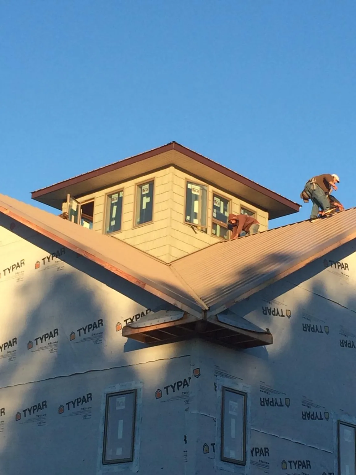 Roofers working around a rooftop cupola on a new metal roof at sunset — Roof Waterproofing in Savona by Roofing Brothers